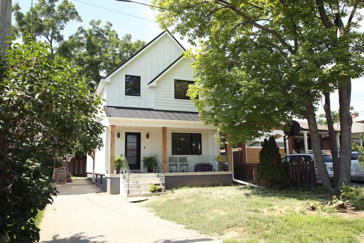Exterior of a completed second storey addition on a Toronto home, with new upper-floor windows and siding