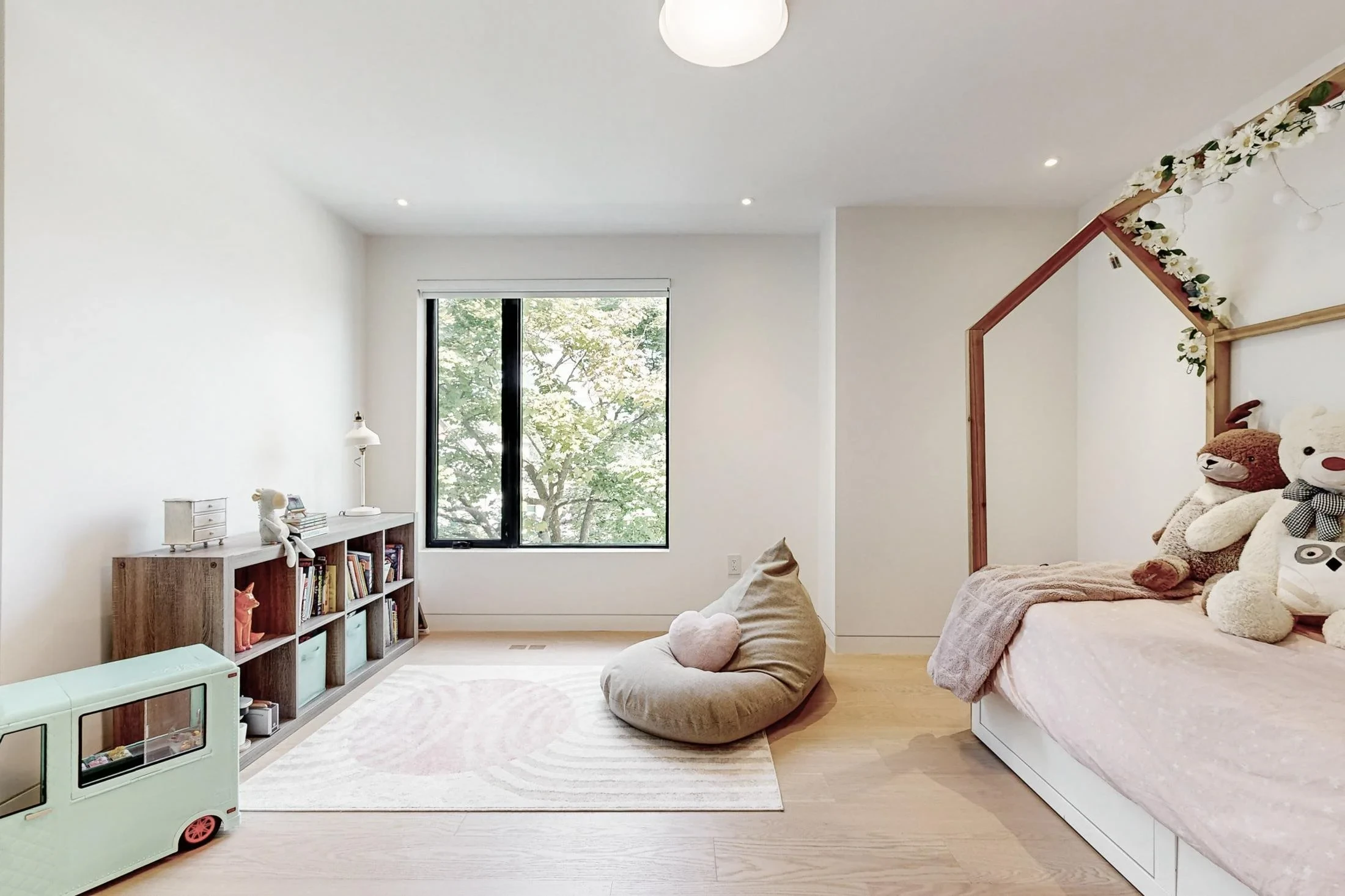 Children's bedroom with a house-frame bed, plush toys, mint storage cubbies, and a beanbag.