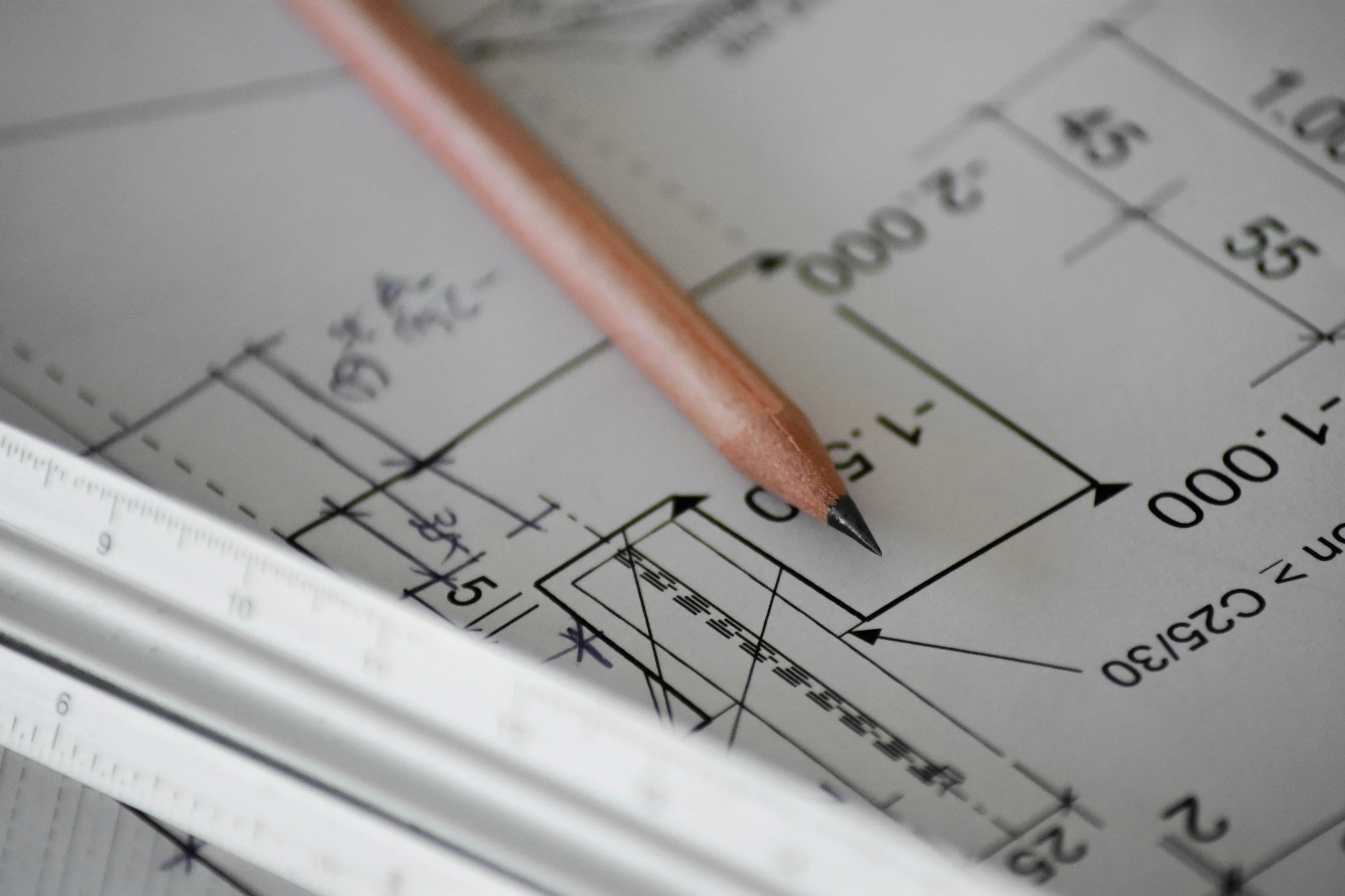 Close-up of an architectural blueprint with a wooden pencil pointing at detailed measurements and design elements.