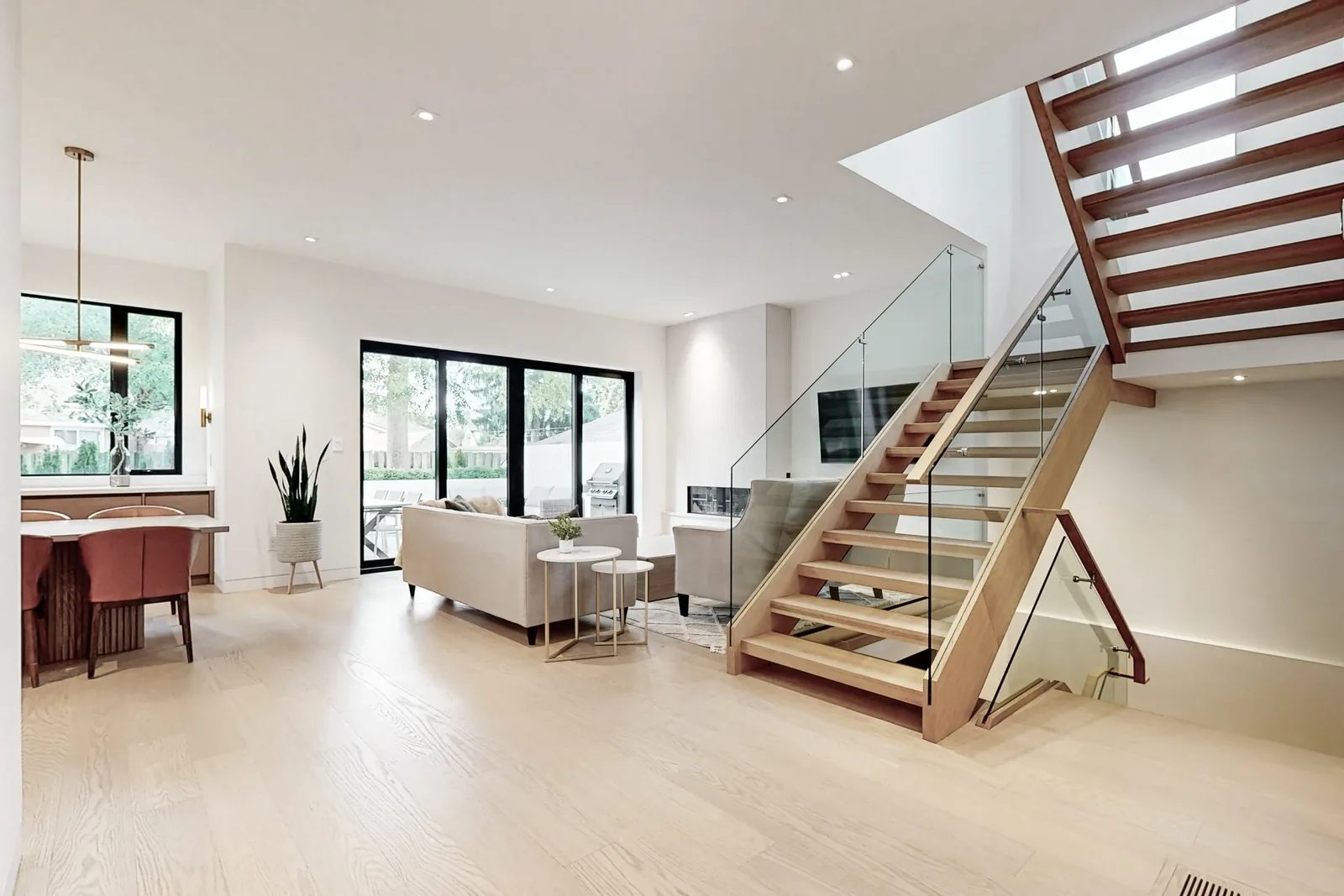 Wide open concept main floor with open riser staircase glass railing and walk out sliding doors to the backyard.