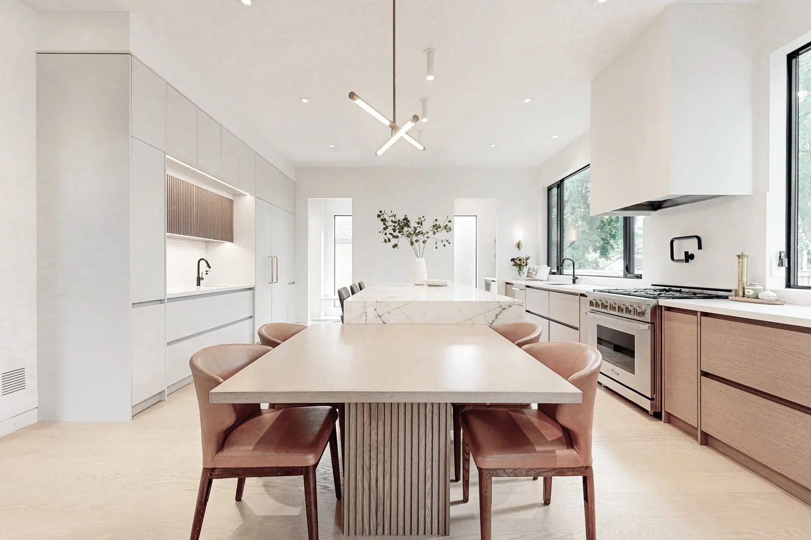 Editorial hero view of the open concept kitchen with oversized marble island and sculptural brass chandelier.