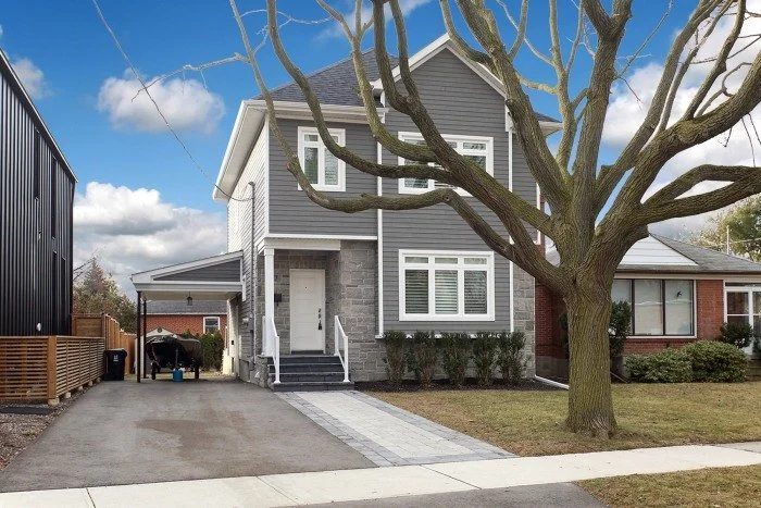 Finished two-storey Toronto home exterior with grey siding, white trim, stone cladding, and a front driveway.