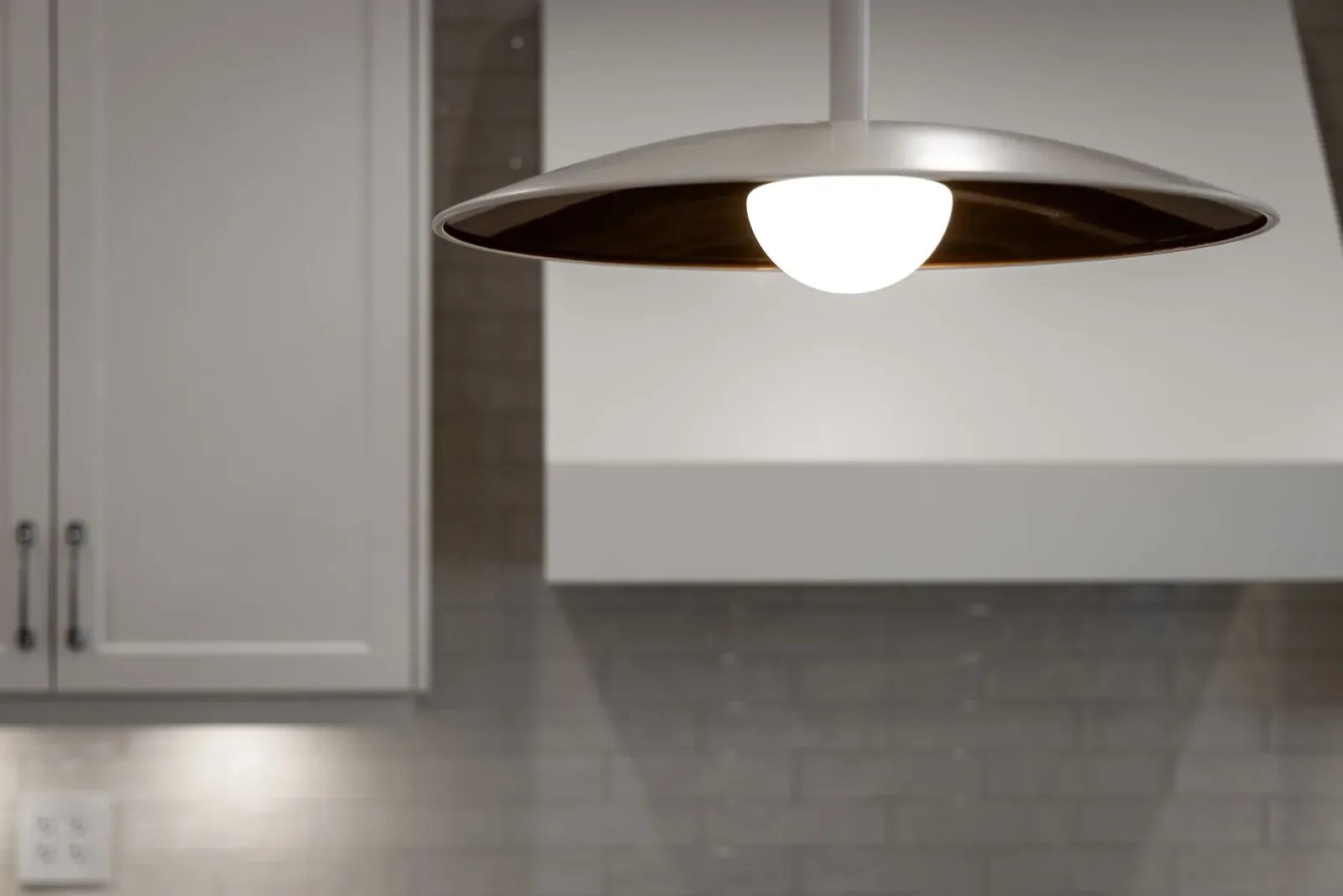 A white saucer pendant with a bronze interior hangs above the island.