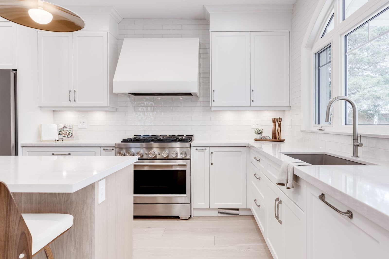 Tight on the custom hood surround, the upper shaker cabinetry and the arched window casing beside it.