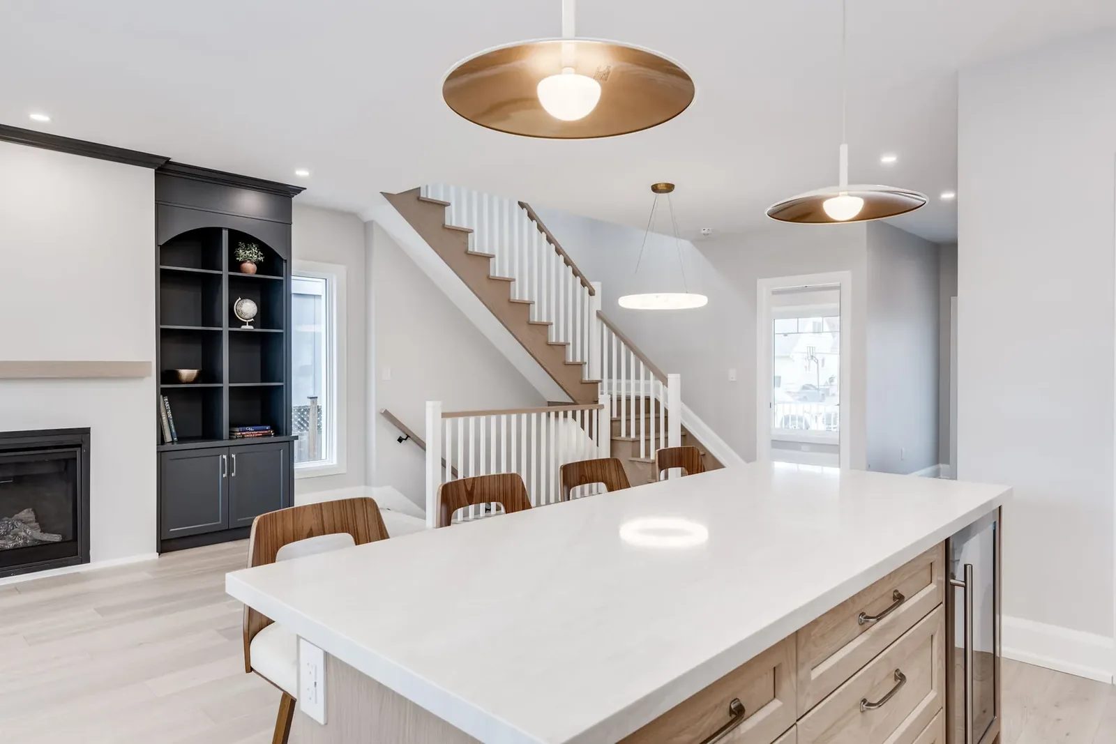 Island end with the oak staircase and the dark arched built-ins rising behind the counter stools.
