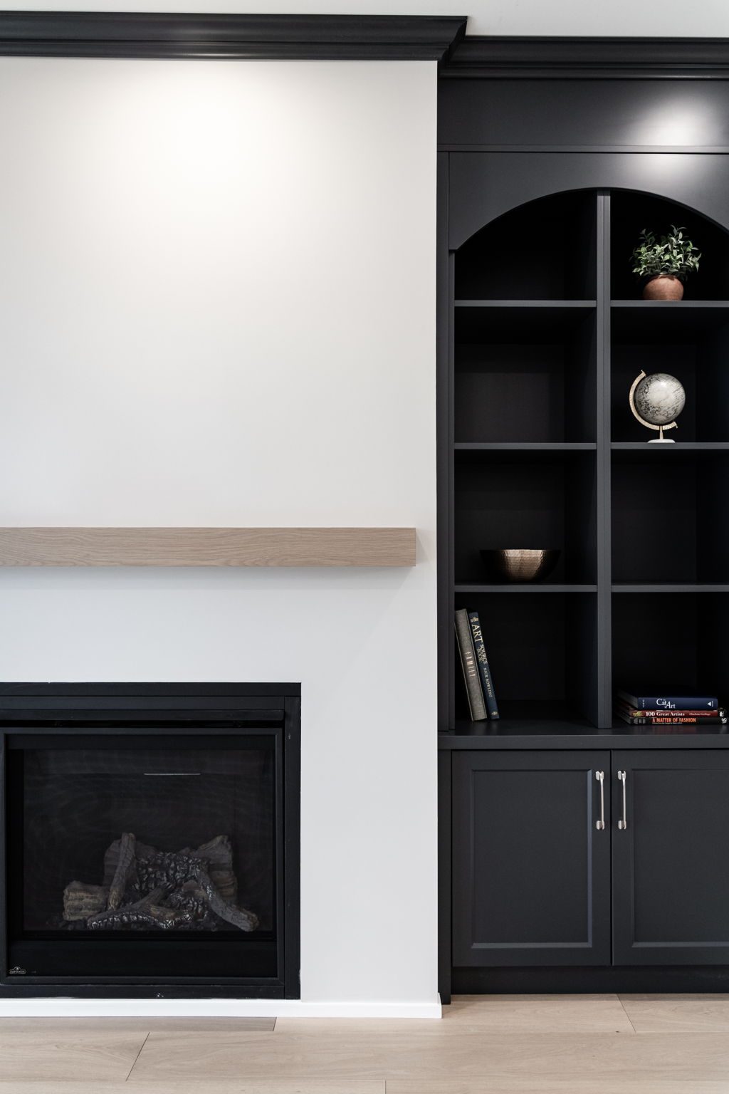 Fireplace surround with a floating oak mantel and the dark arched built-in beside it.