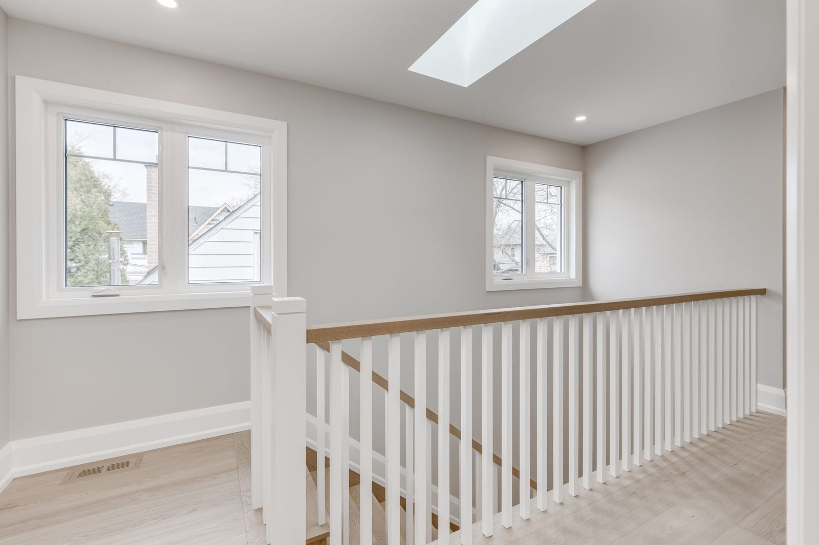 Upper landing lit by a skylight, with the full railing run and white-trimmed windows.