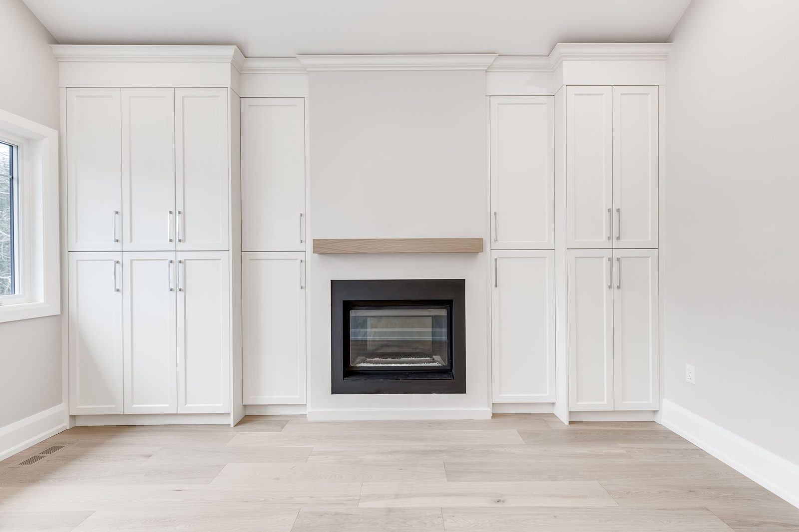 Built-in fireplace wall in the primary bedroom, with flanking tall white cabinetry and an oak mantel shelf.