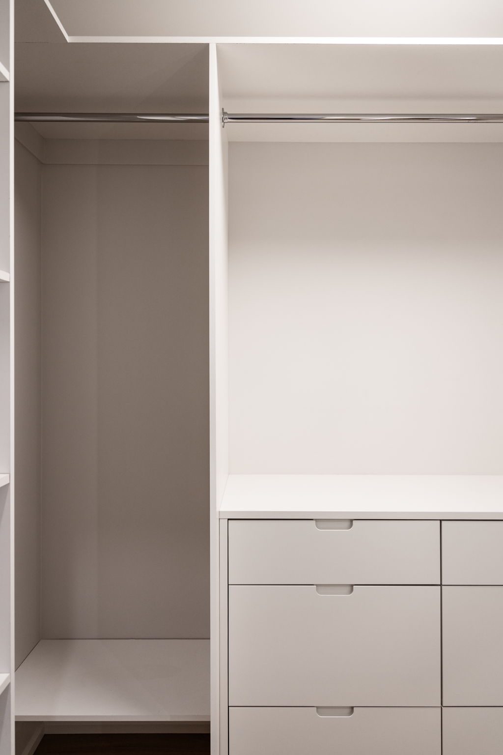 Built-in closet system with a hanging rail, open shelving and a bank of drawers.