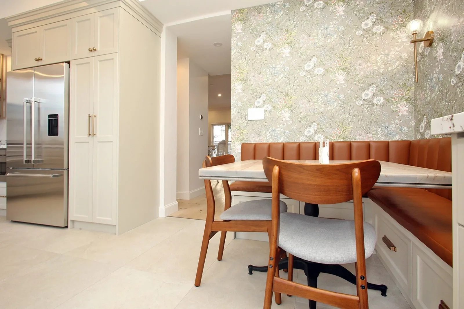 Bright kitchen breakfast nook with colourful floral wallpaper, caramel banquette seating and warm wood chairs.
