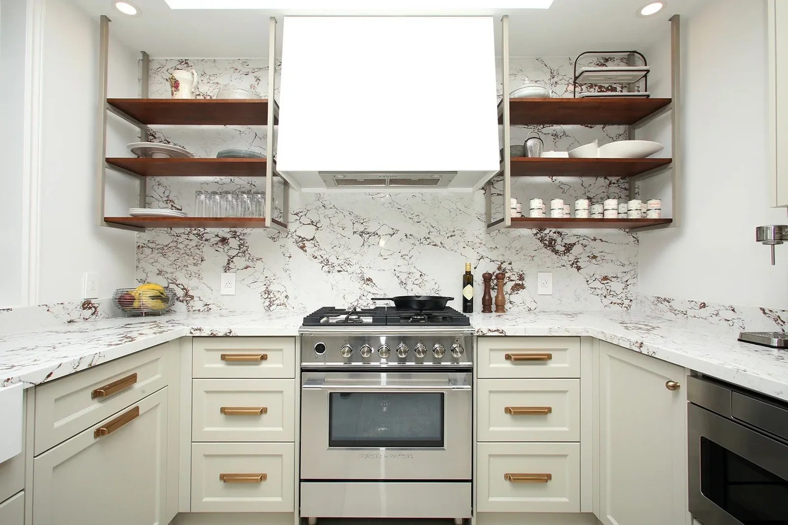 Bright finished kitchen with veined stone surfaces, open walnut shelves and brass hardware.