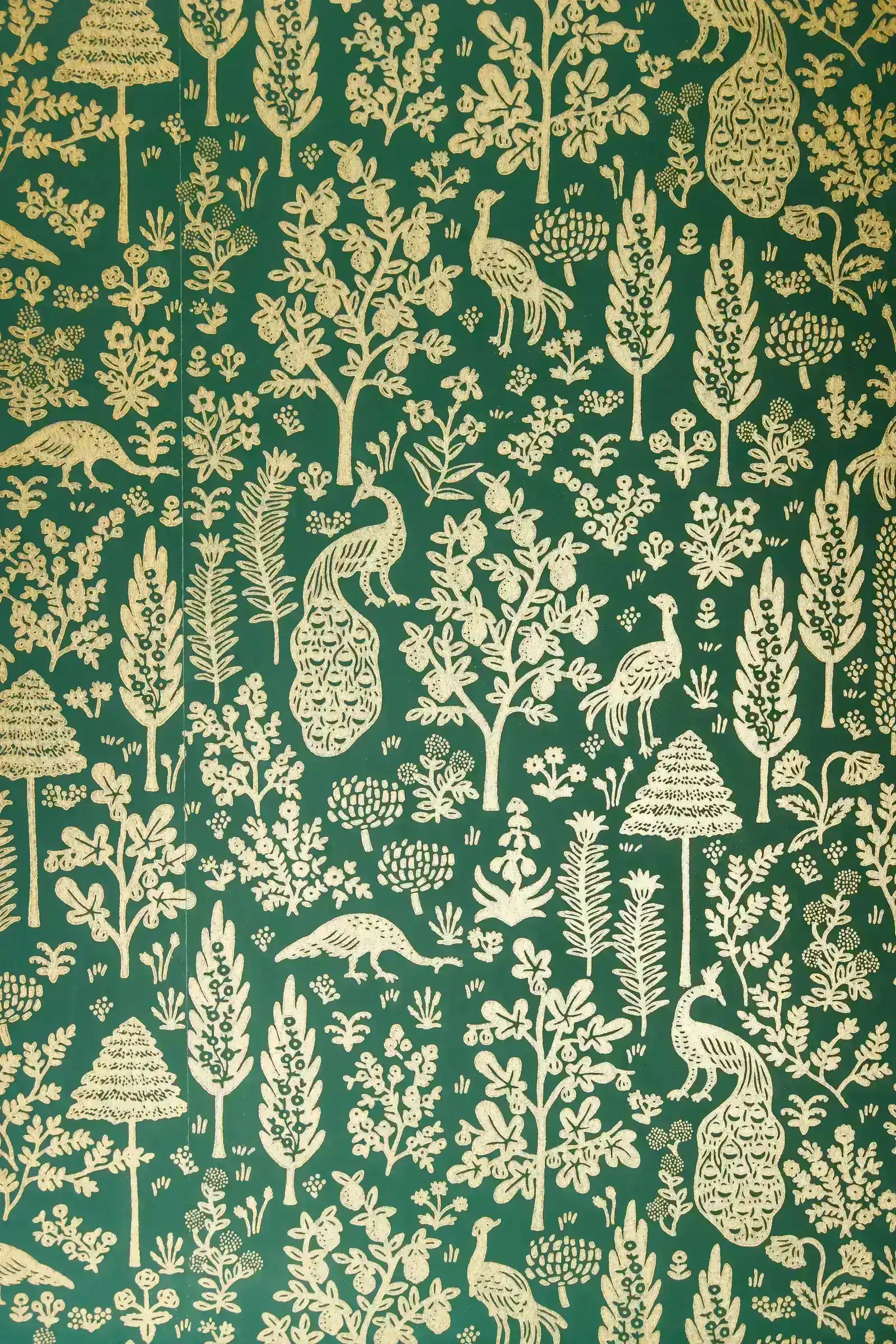 Detail of green and gold botanical wallpaper with peacocks and stylised trees.