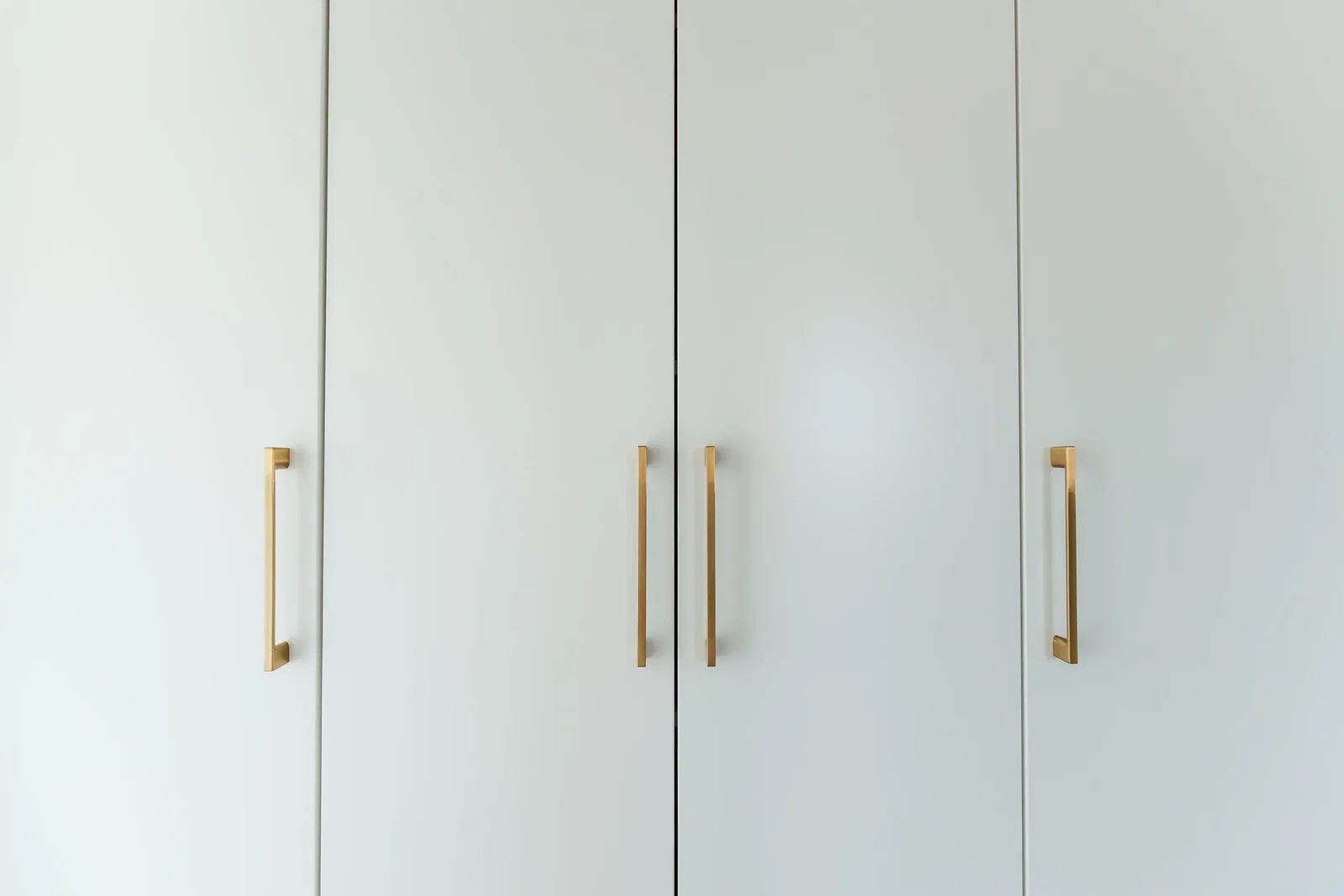 Close view of built-in closet slab doors with long polished brass bar pulls.