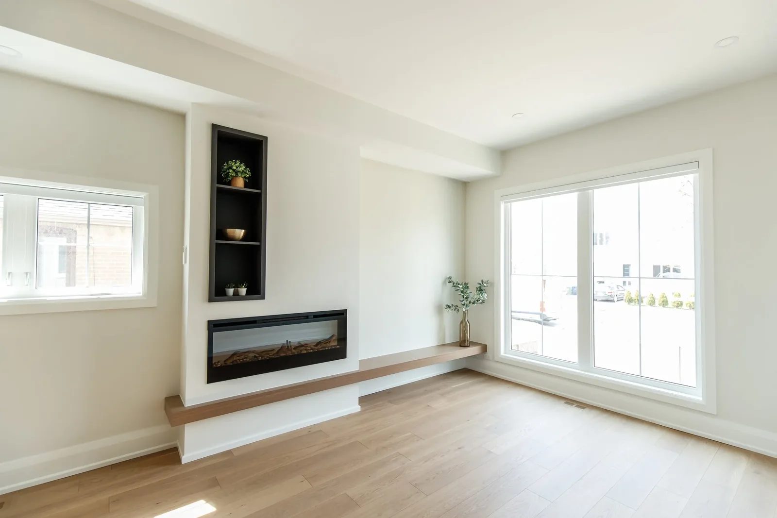 Living room with built-in linear fireplace and cantilevered oak bench beneath tall windows.
