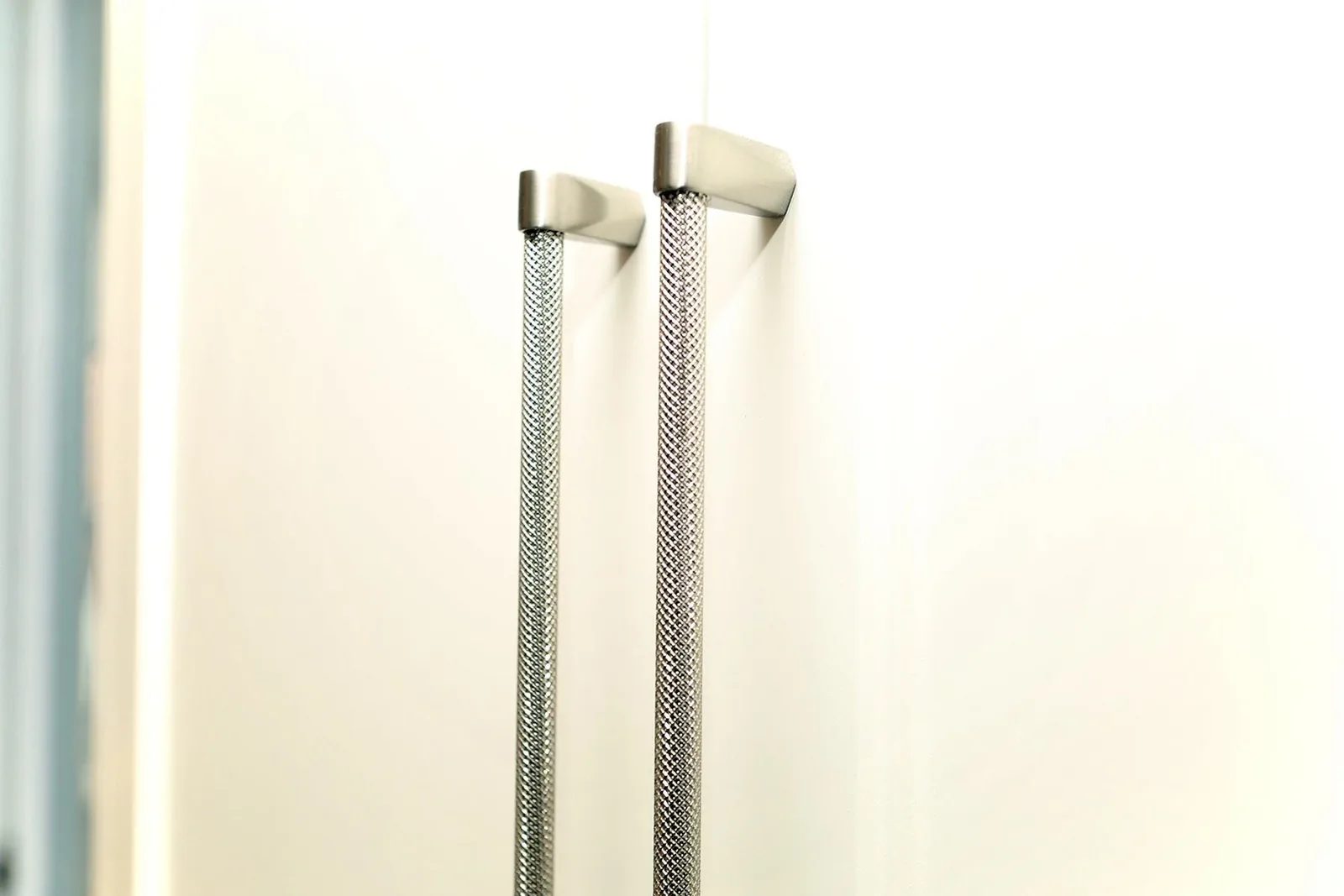 Warm white flat-panel kitchen cabinetry with textured metal pulls catches soft natural light.