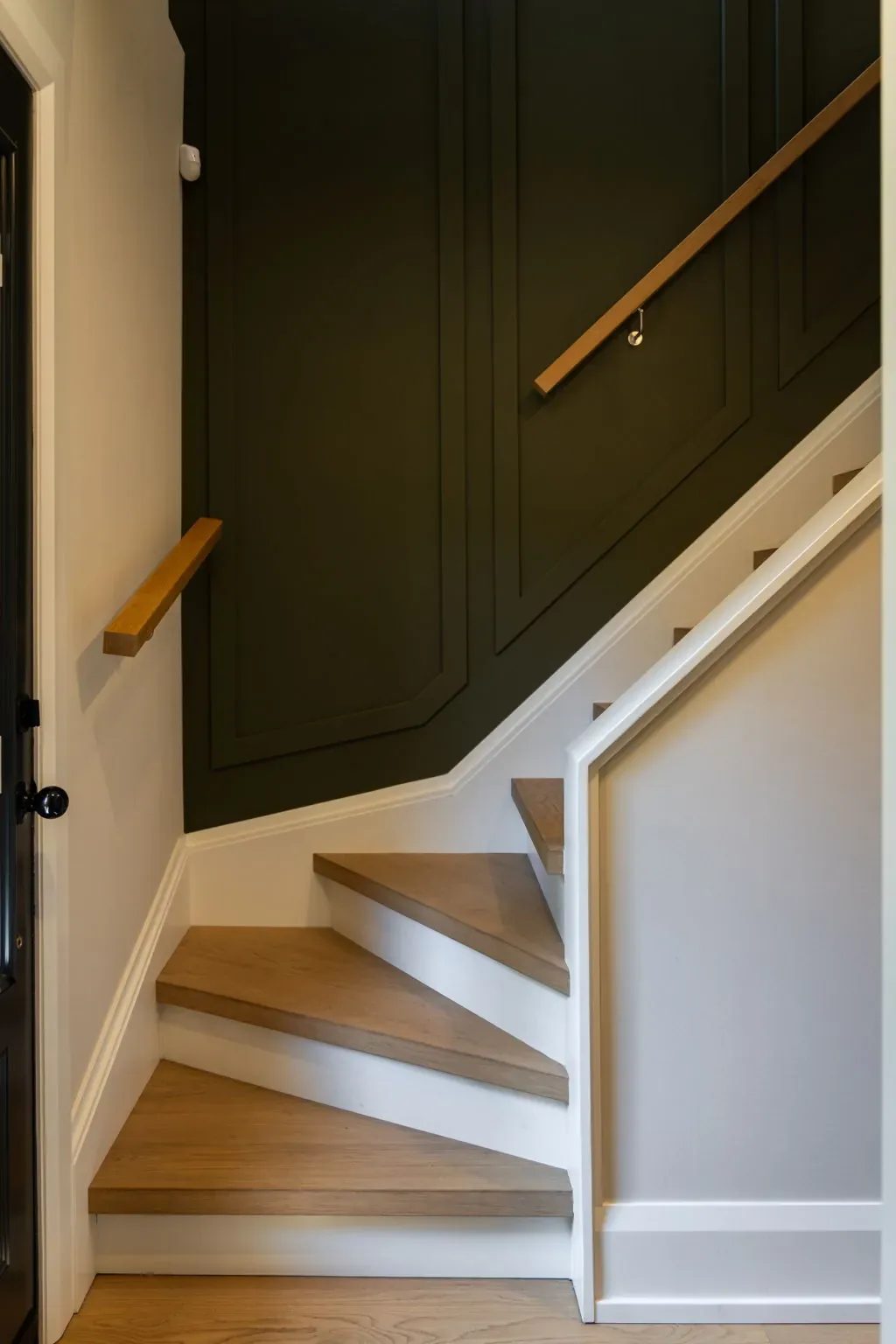 The staircase with deep green panelling running alongside it.