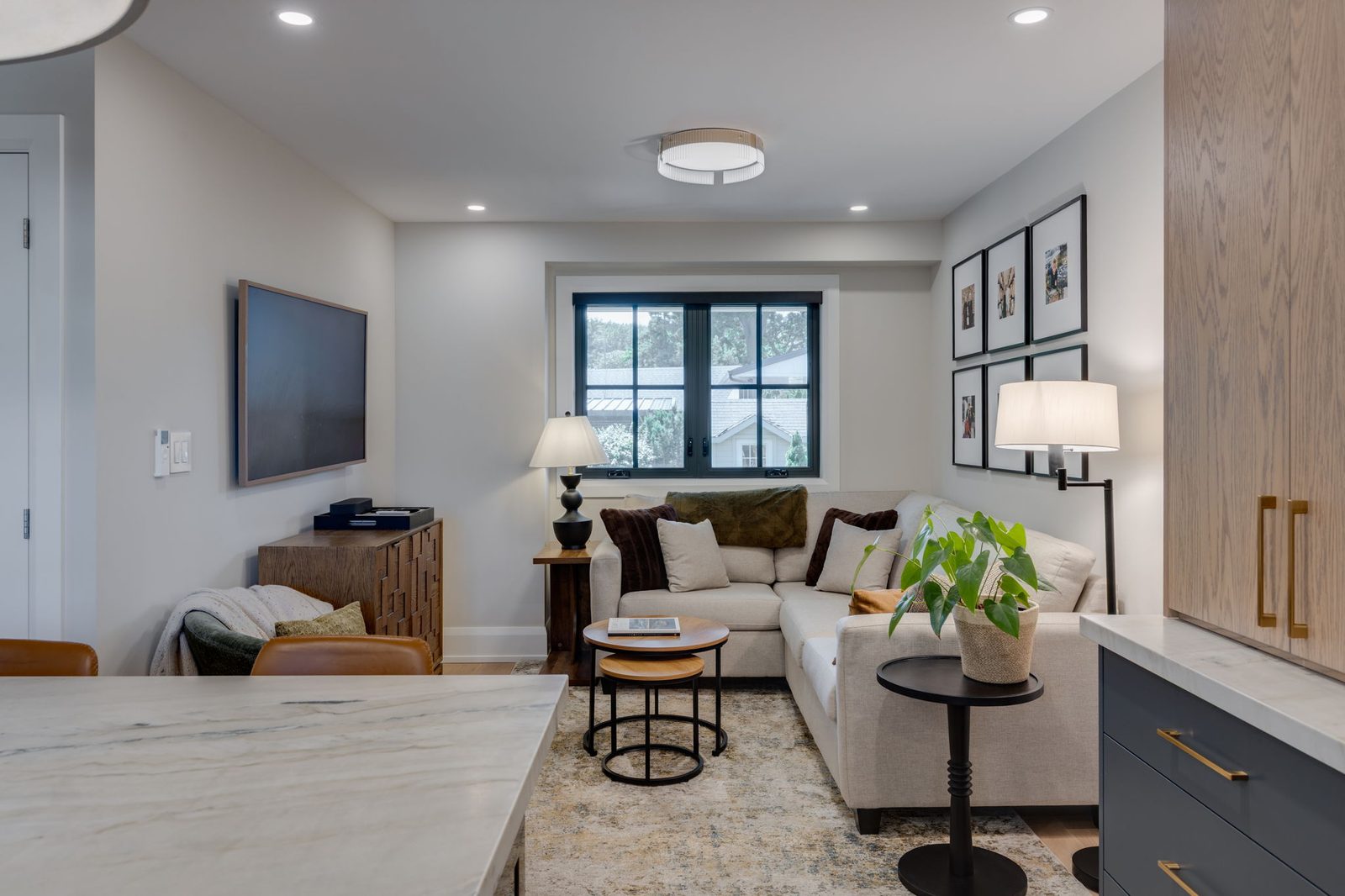 White oak millwork feature wall with an integrated television, tall oak cabinetry with brass pulls and navy base cabinets.
