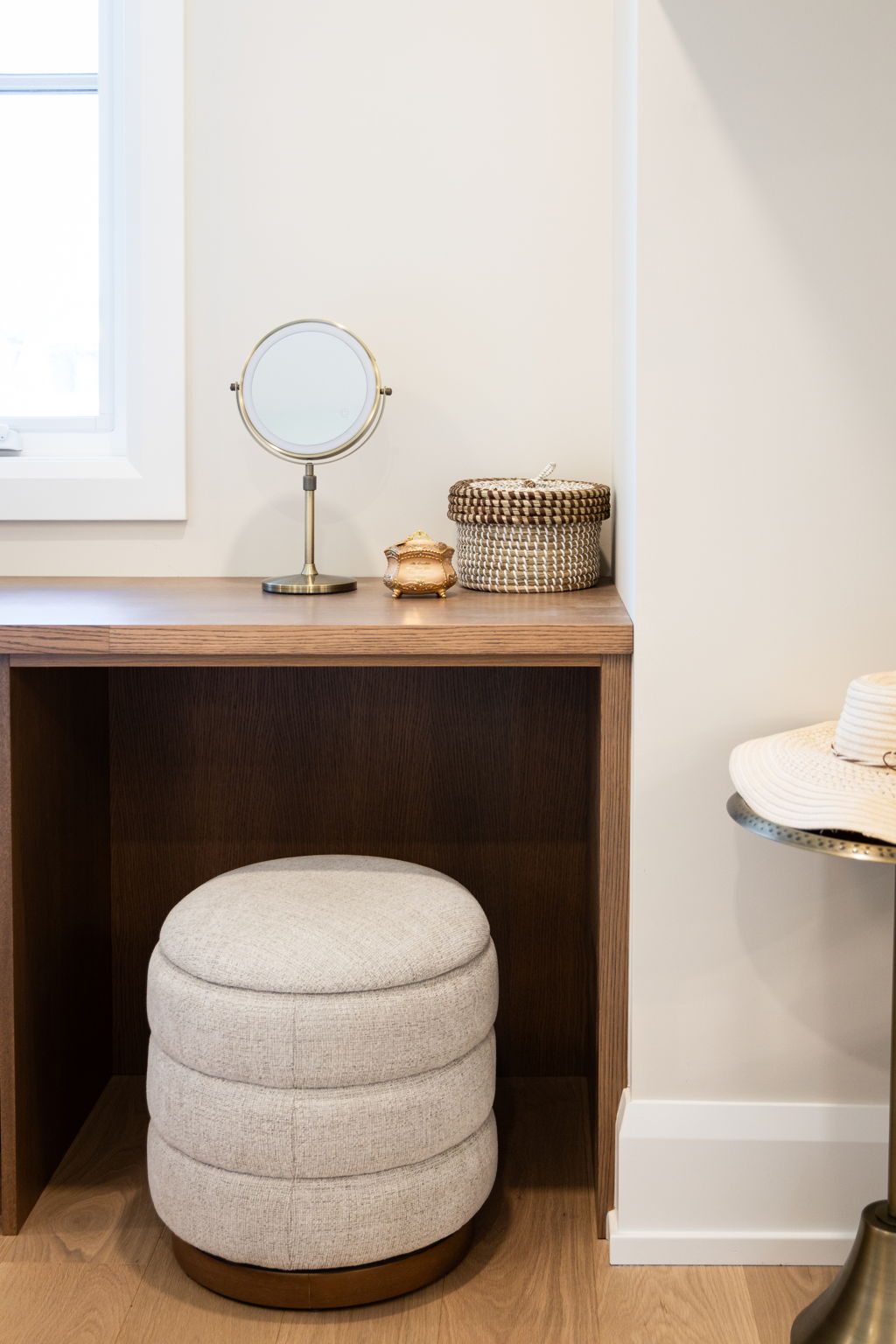Integrated vanity desk with the knee hole cut into the walnut dresser run and an upholstered stool tucked beneath.