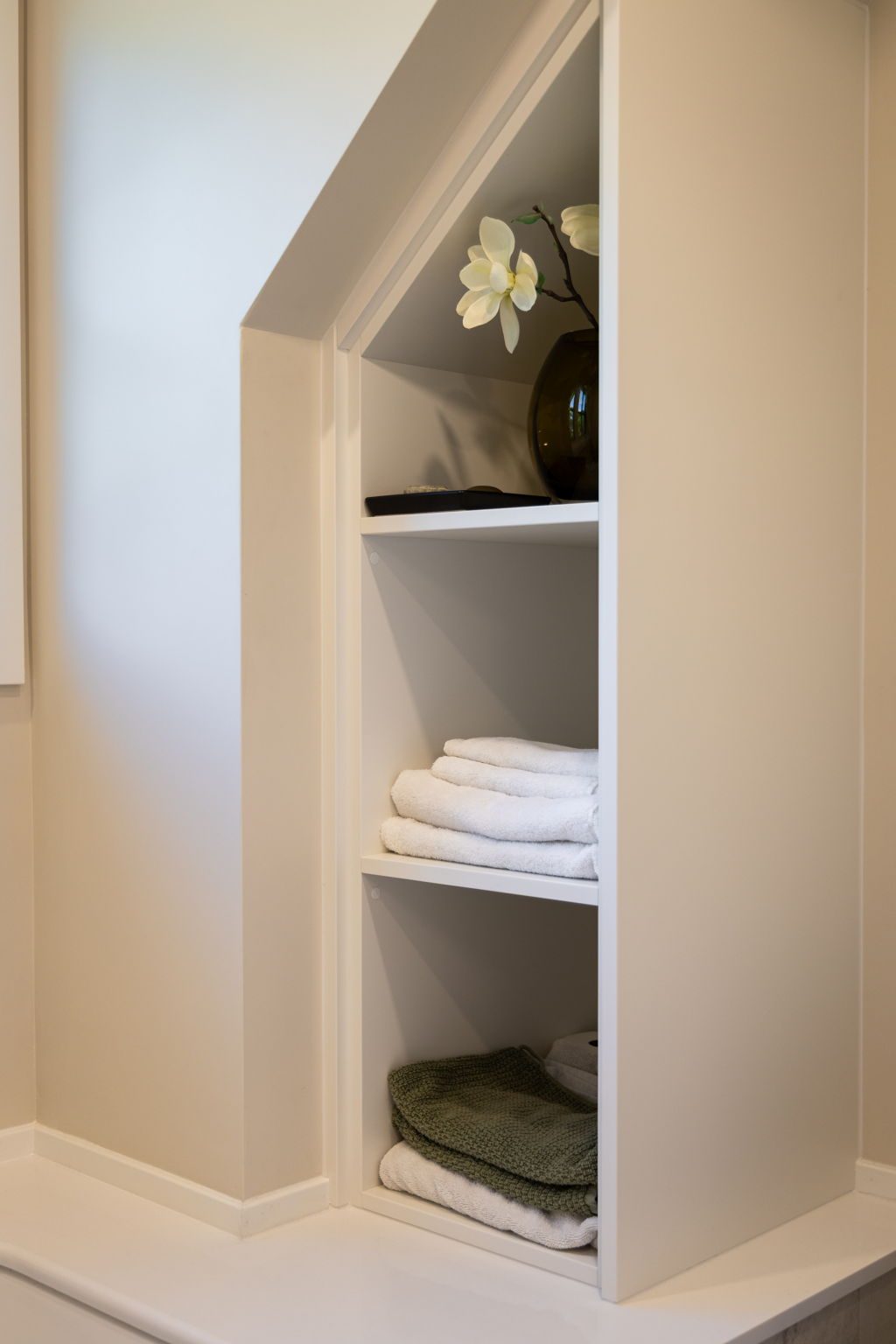 Built-in linen shelving fitted under the roof slope, holding folded towels and throws.
