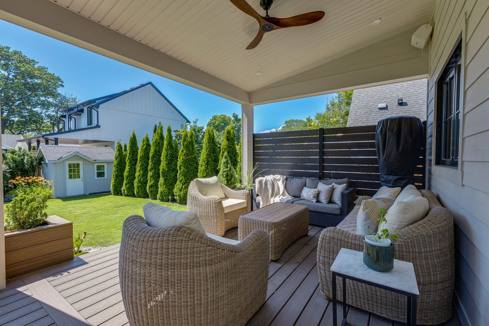 Covered rear porch with painted framing and soffit, square posts, a horizontal slat privacy screen and a composite deck.