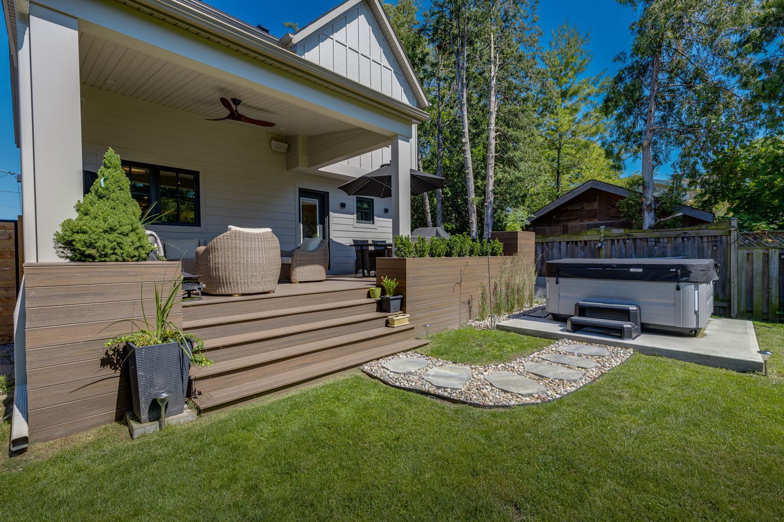 Composite deck, stair treads and planter walls seen from the lawn, with the covered porch structure behind.