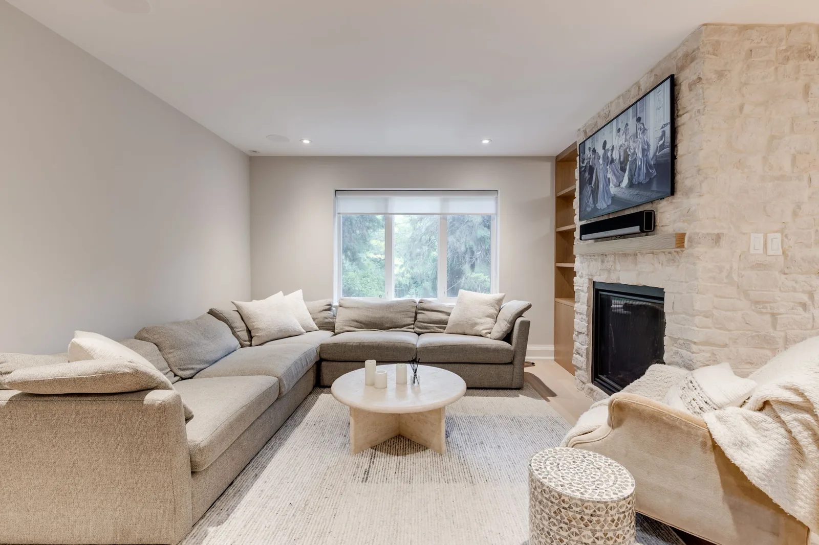 Living room with an L-shaped sofa facing a natural stone fireplace and a wall-mounted television.