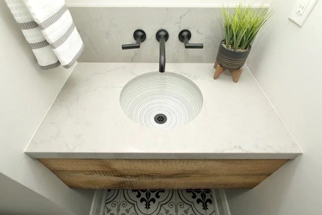 Powder room vanity with a marble-look counter, black wall-mounted faucet, and wood drawer front, Timeless Elegance project
