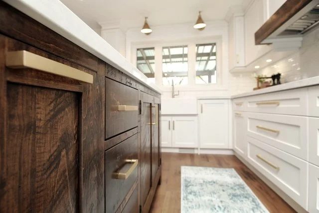 Rustic wood island with brass pulls facing white kitchen cabinetry, Timeless Elegance project