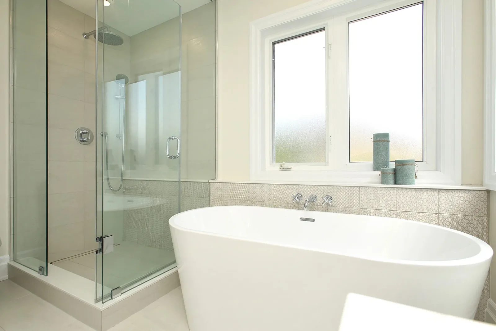 Bright renovated bathroom with a freestanding tub, glass shower, and a warm white colour palette.