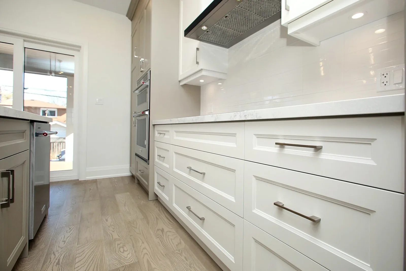 White kitchen cabinetry with a marble-look backsplash and wood floors, Urban Farm Chic project