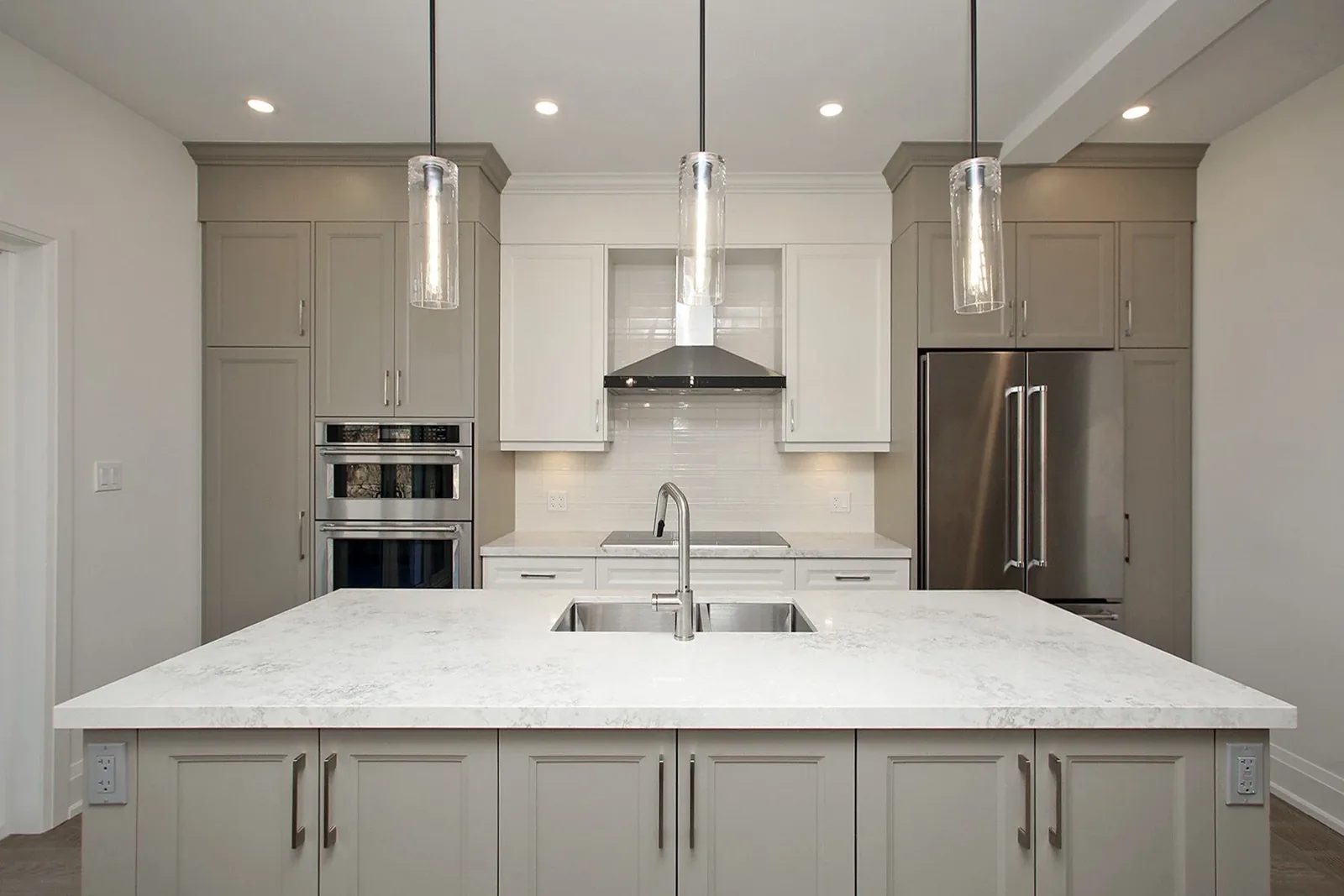 Bright transitional kitchen with a large island, warm grey cabinets, quartz counters, and stainless appliances.